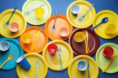 Renkli arkaplanda plastik sofra takımı ve konfeti