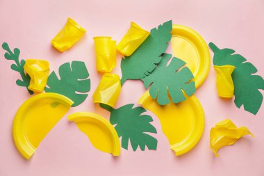 Plastik çöp ve renkli arka planda kağıttan yapılmış tropikal yapraklar