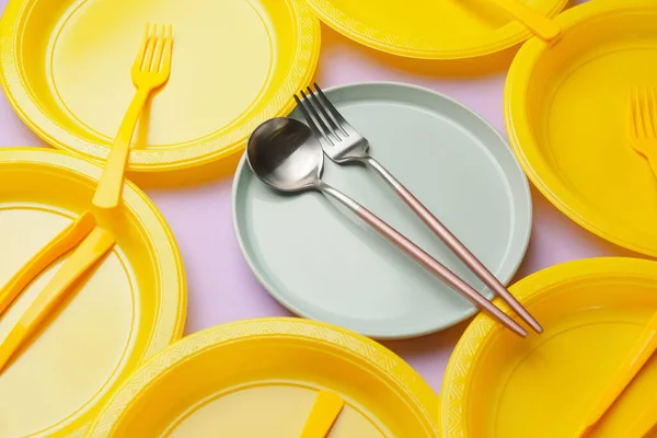 Plastic and ceramic tableware on color background