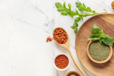 Hafif arka planda farklı baharatlı kâseler ve kaşıklar.