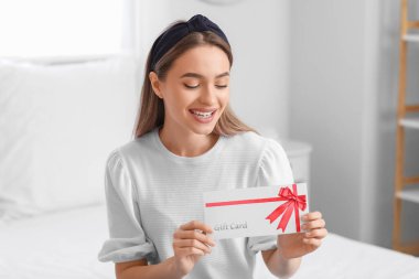 Evde hediye kartı olan güzel bir genç kadın.