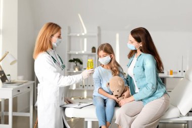 Küçük kızıyla birlikte bir kadın klinikteki çocuk doktorunu ziyaret ediyor.