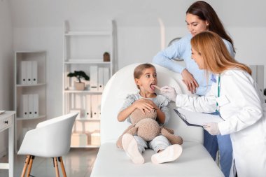 Pediyatrist küçük kızı klinikte muayene ediyor.