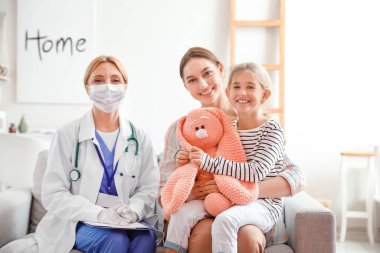 Çocuk doktoru, küçük kız ve annesi evde.