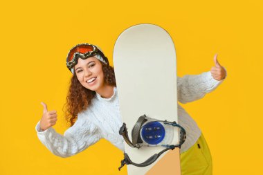 Kadın snowboardcu renk arkaplanda başparmak yukarı gösteriyor