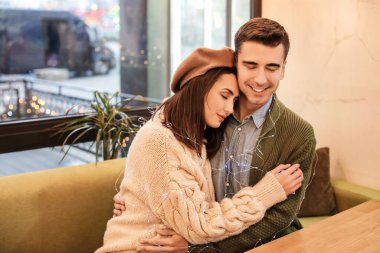 Mutlu genç çift Noel arifesinde kafede oturuyor.