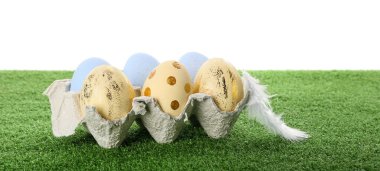 Beyaz arka planda çimenlerin üzerinde paskalya yumurtaları