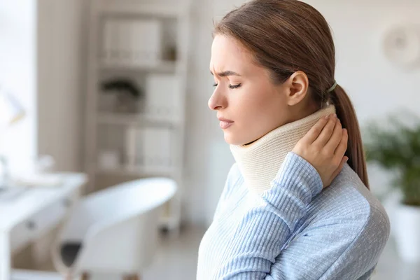 Young woman with cervical collar on neck suffering from pain at home