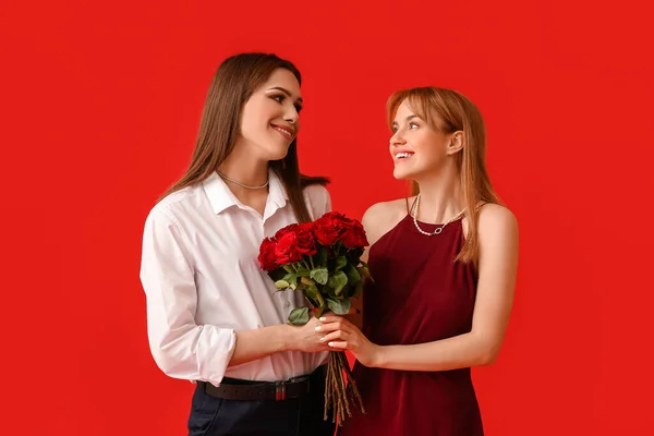 若いトランスジェンダーのカップルは背景色に花を咲かせます バレンタインデーのお祝い — ストック写真