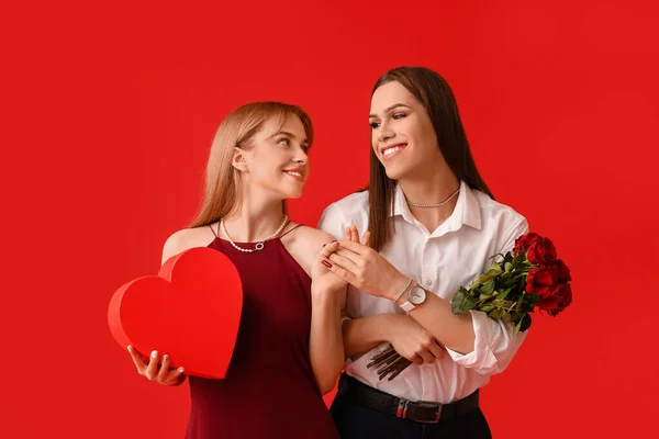 Junges Transgender Paar Mit Blumen Und Geschenk Auf Farbigem Hintergrund — Stockfoto