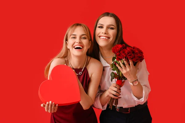 色の背景に花や贈り物を持つ若いトランスジェンダーのカップル バレンタインデーのお祝い — ストック写真