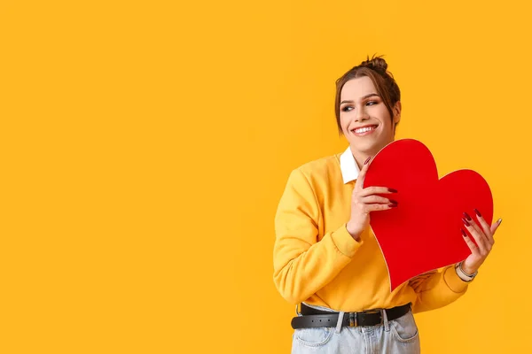 色の背景に赤いハートを持つ若いトランスジェンダーの女性 バレンタインデーのお祝い — ストック写真