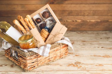 Tahta arka planda ürünleri olan bir hediye sepeti.