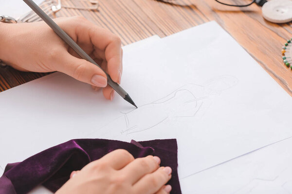 Женщина-модельер работает с эскизом в студии, крупным планом