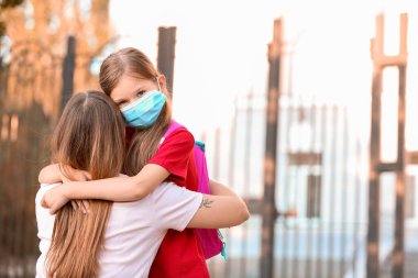 Anne okula yakın bir yerde tıp maskeli kızına veda ediyor. Coronavirüs salgını