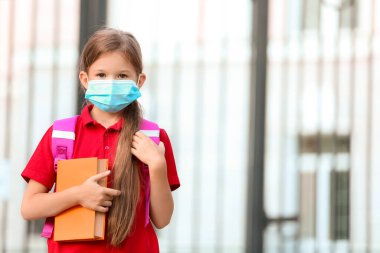 Okulun yakınında maske takan küçük bir kız. Coronavirüs salgını