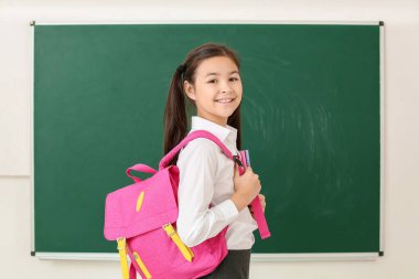 Sınıfta karatahtanın yanındaki küçük kız.