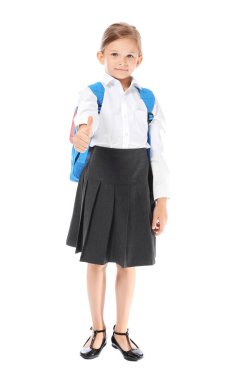 Küçük liseli kız beyaz arka planda baş parmak hareketi gösteriyor.