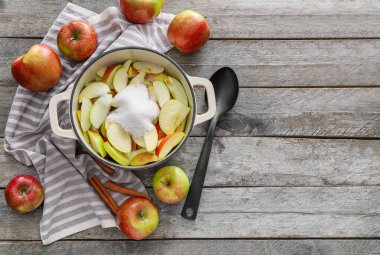 Ahşap zemin üzerinde kesilmiş elma ve şeker ile tencere pişirme