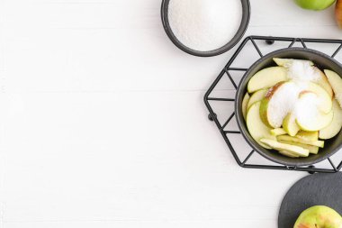 Kesik elmalı kızartma tavası ve hafif arkaplanda şeker