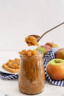Kavanoz ve kaşık hafif arkaplanda elma reçeli