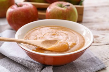 Ahşap arka planda elma reçeli ile kase ve kaşık