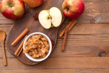 Tatlı elma reçelli kase ve ahşap zemin üzerinde tarçın