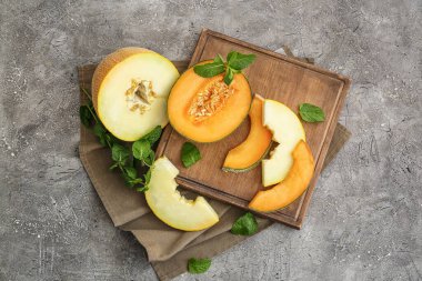 Gri arkaplanda tatlı kesilmiş kavun olan tahta