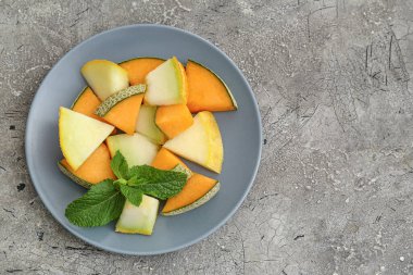 Gri arkaplanda tatlı kesilmiş kavun tabağı