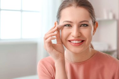 Süngerli güzel bir kadın evde makyaj yapıyor.