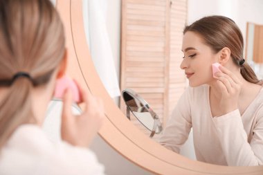 Süngerli güzel bir kadın evde makyaj yapıyor.