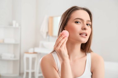 Süngerli güzel bir kadın evde makyaj yapıyor.