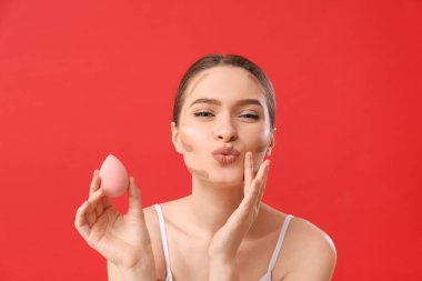 Güzel bir genç kadın renk arkaplanına karşı makyaj yapıyor.