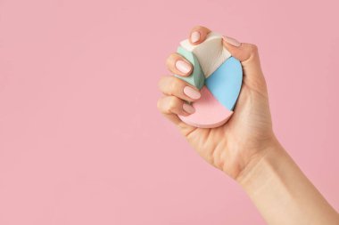 Renkli arka planda makyaj süngeri olan el