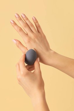 Renkli arka planda makyaj süngeri olan eller