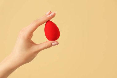 Renk arkaplanında makyaj süngeri olan el