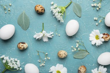 Renkli arka planda Paskalya yumurtaları ve bahar çiçekleriyle kompozisyon