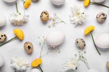 Hafif arka planda Paskalya yumurtaları ve bahar çiçekleriyle kompozisyon