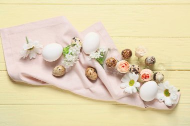 Renkli ahşap arka planda Paskalya yumurtaları ve bahar çiçekleriyle kompozisyon