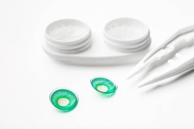 Beyaz arkaplanda cımbız, kontak lensler ve kabın