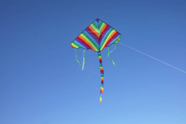 Mavi gökyüzünde uçan renkli uçurtma