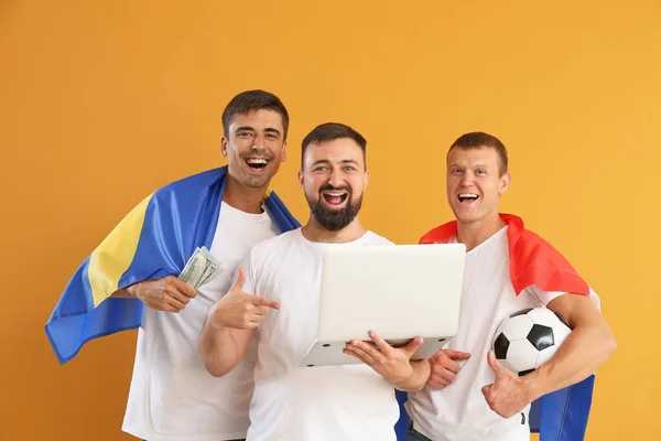 Men with laptop placing sports bet on color background