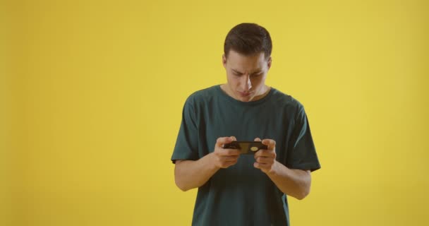 Hombre Joven Con Teléfono Móvil Jugando Juego Fondo Color — Vídeos de Stock