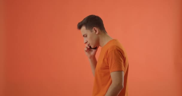 若い男の話で携帯電話で色の背景 — ストック動画