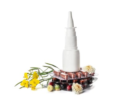 Beyaz arka planda damla, çiçek ve haplarla dolu bir şişe