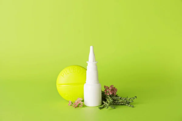 Bottle with drops, flowers and container for pills on color background