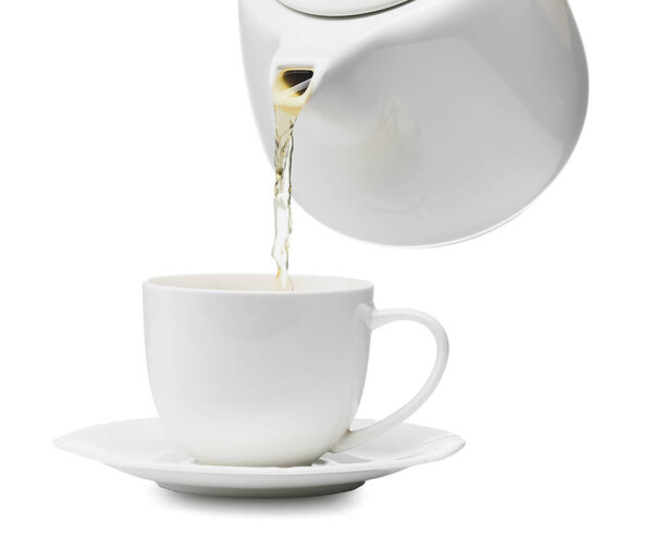 Наливание горячего чая из чайника в чашку на белом фоне