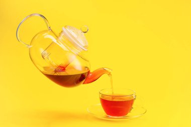 Çaydanlıktan fincana renk arkaplanı olarak sıcak çay dökülüyor