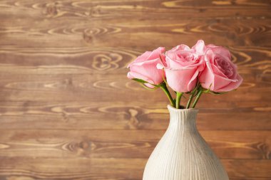 Ahşap arka planda vazoda güzel pembe güller