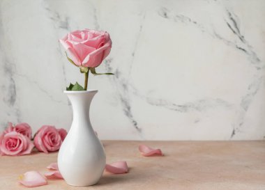 Masanın üzerinde, açık arkaplanda duran güzel pembe gül.